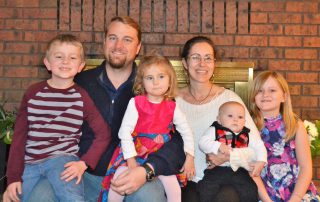 missionary family in front of a red brick fireplace