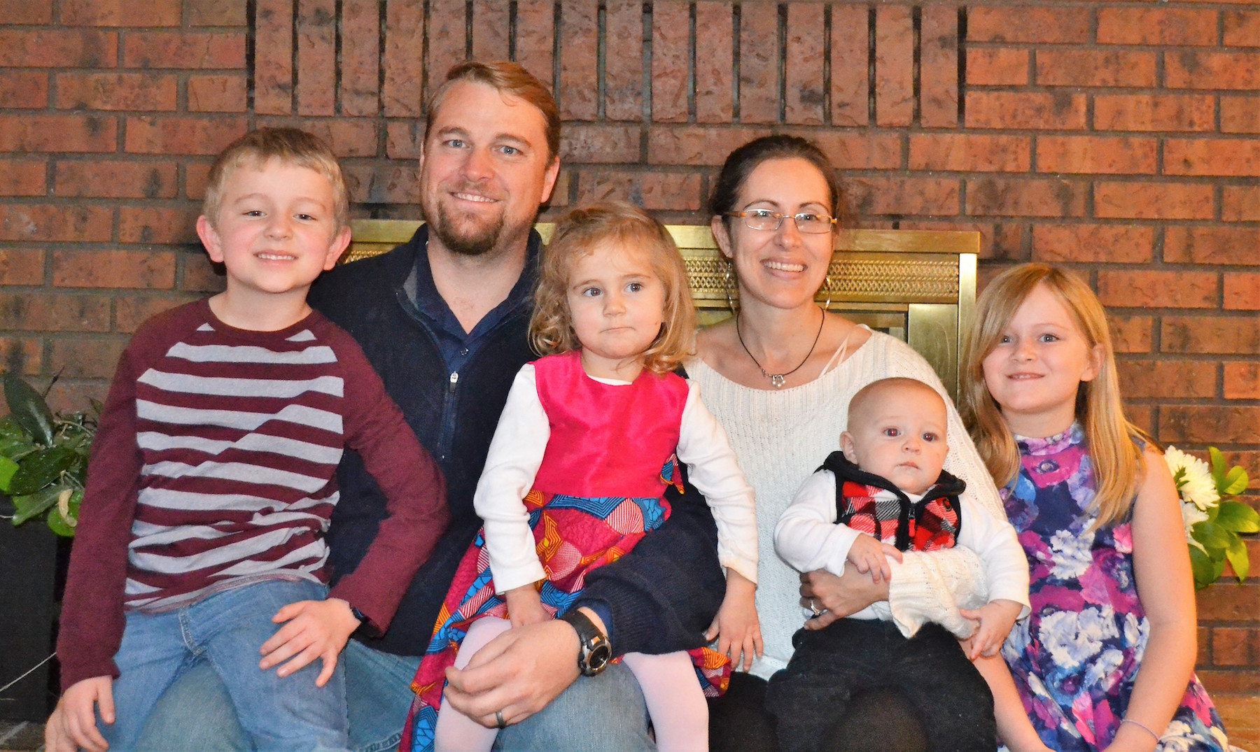 missionary family in front of a red brick fireplace