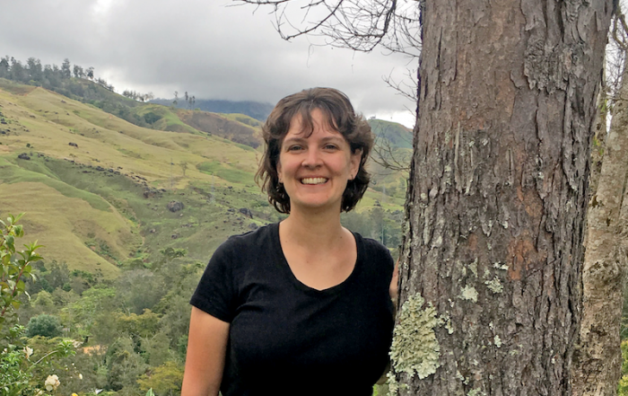 Kristen standing by a tree with a Papua New Guinea mountain valley in the background