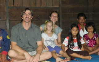 missionaries and national children sitting crosslegged on floor