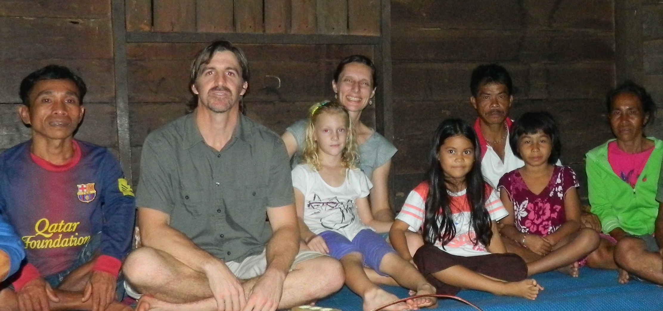 missionaries and national children sitting crosslegged on floor