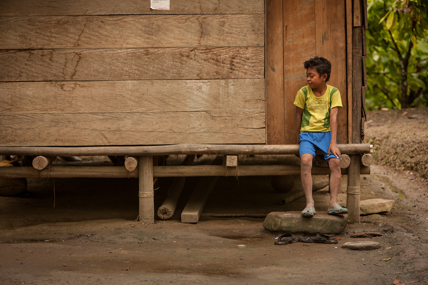 boy sitting on porch of wood house