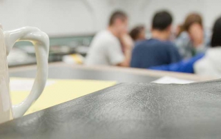 Mug, bible, and group of students in classroom