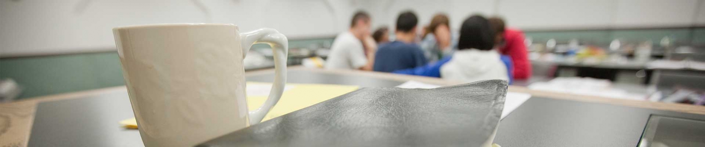 Mug, bible, and group of students in classroom