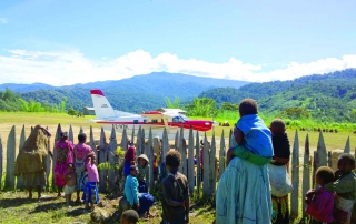 Women and children watch Kodiak plane land