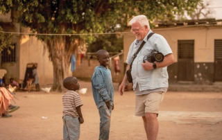 man with camera talks to African boys