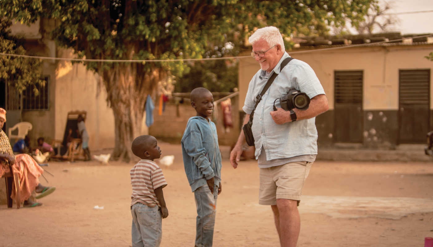 man with camera talks to African boys