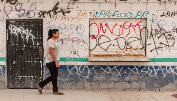 Girl walking in front of wall with graffiti