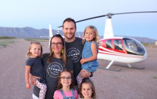 man and woman with their 4 daughters in Arizona with a helicopter in the background