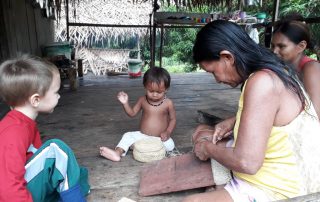 missionary's child sits with locals in a grass hut