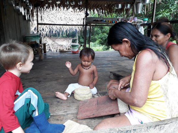 missionary's child sits with locals in a grass hut