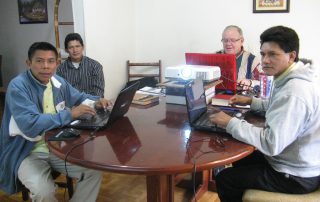 missionary and language helpers translating Bible portion in a house at a table