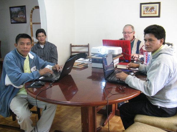 missionary and language helpers translating Bible portion in a house at a table