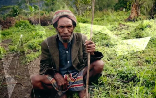 Papua New Guinean man squatting beside a trail in the mountains