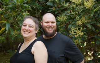 smiling missionaries in front of some shrubs or undergrowth