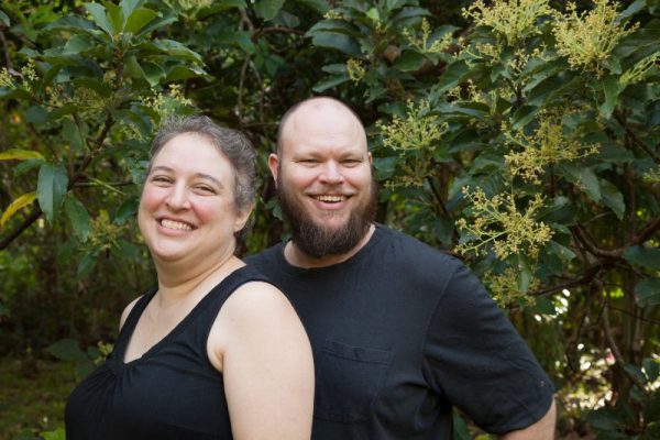 smiling missionaries in front of some shrubs or undergrowth