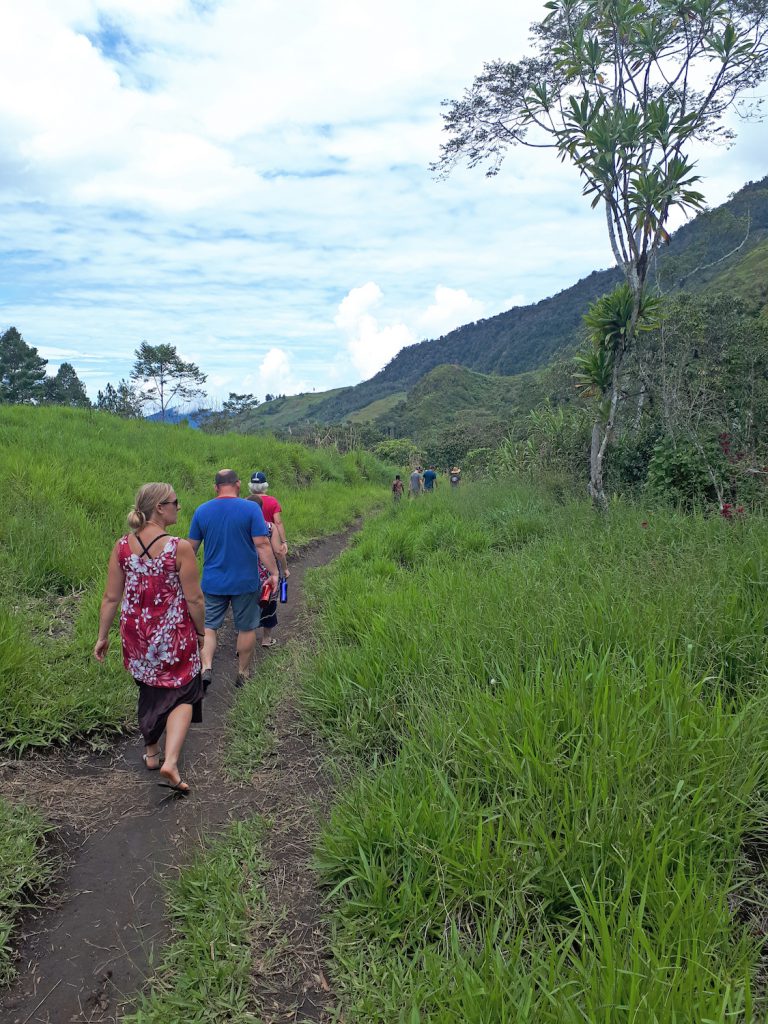 missions trip team members walking along a trail with jungle covered mountain in the background