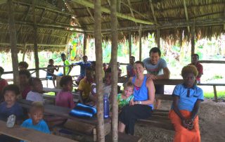 missionaries with locals under a grace roofed shelter