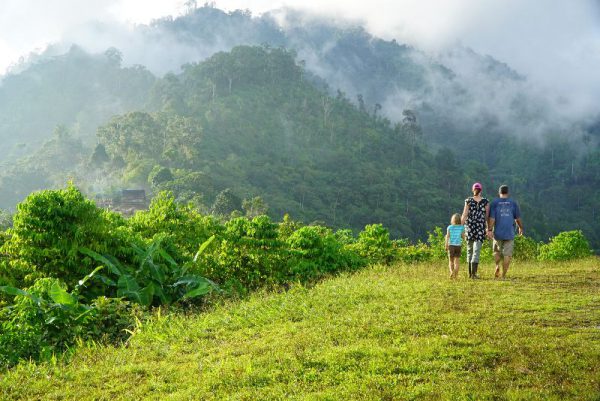 missionary woman and her kids walking near the edge of a mist shrouded valley in Papua New Guinea