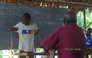 Papua New Guinea man teaching in a hut with no walls