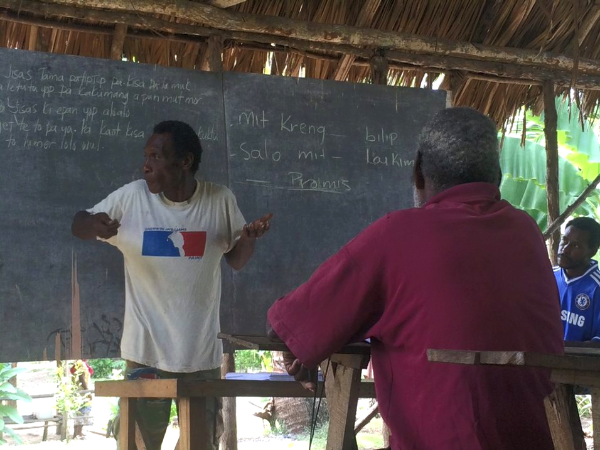 Papua New Guinea man teaching in a hut with no walls