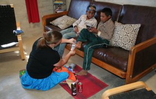 missionary woman serving a boy by bandaging up his foot