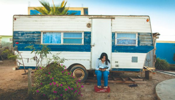 woman reading Bible while sitting on step of her camper trailer