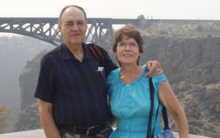 a man and woman standing at a lookout with a bridge in the background