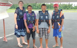 missionary translator with 3 language helpers prepare for a flight in a small plane in Papua New Guinea