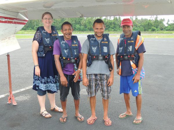 missionary translator with 3 language helpers prepare for a flight in a small plane in Papua New Guinea