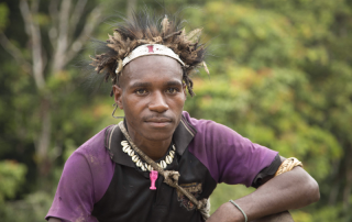 young Papua New Guinean man with feathered hat, bead necklace and string bag