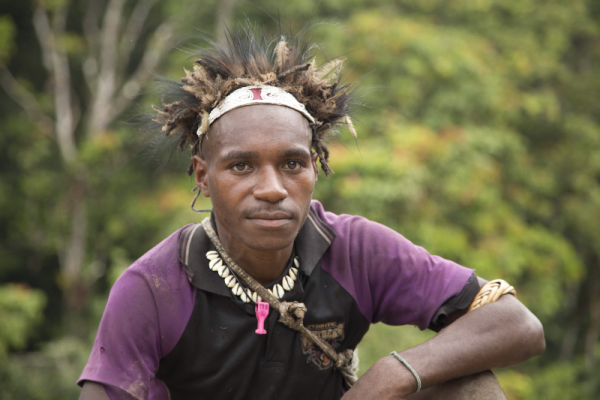 young Papua New Guinean man with feathered hat, bead necklace and string bag