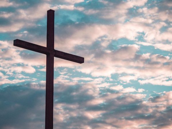 empty cross with a cloudy sunset sky in the background