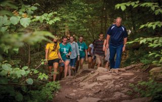 Steve and a group of young people walking in the woods at Wayumi