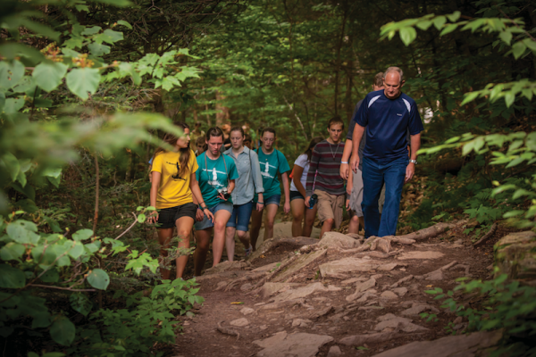 Steve and a group of young people walking in the woods at Wayumi