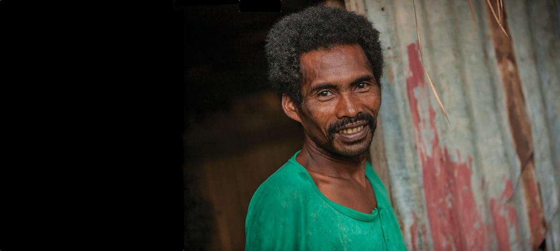 smiling man standing by a metal-sheet wall
