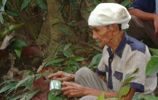 man sitting under a tree with a tin can