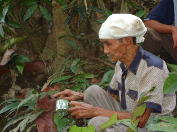 man sitting under a tree with a tin can