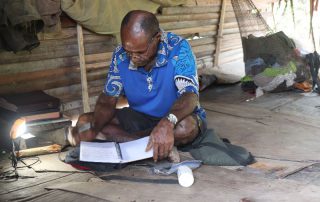 Namoleya studying the Bible in his hut