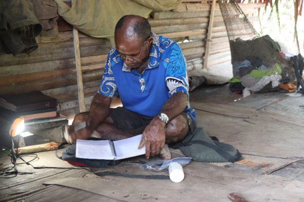 Namoleya studying the Bible in his hut