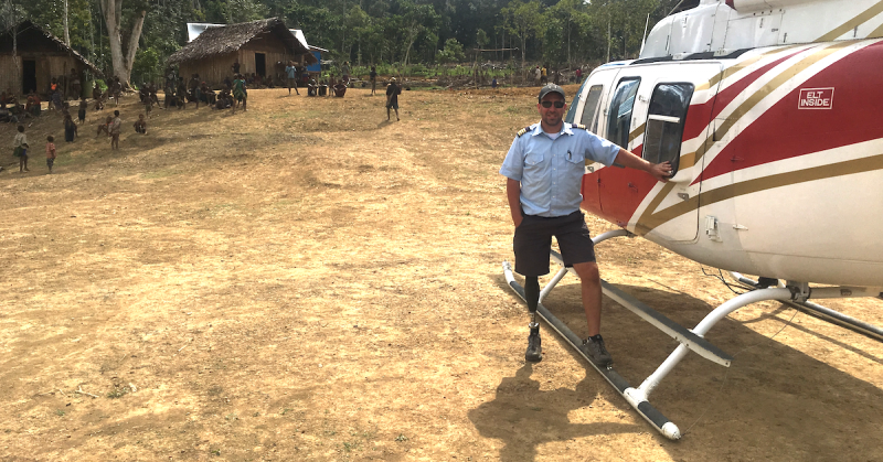 Paraplegic helicopter pilot standing by helicopter in Papua New Guinean village