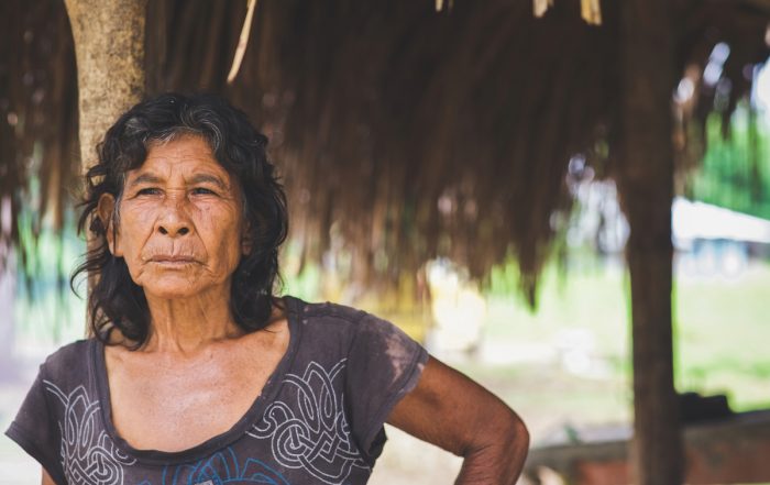 woman standing by grass-roofed hut