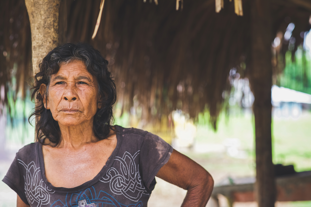 woman standing by grass-roofed hut