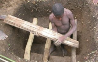 a man down in a hole preparing a grave for a small child