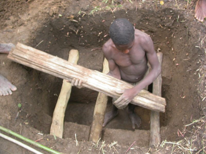 a man down in a hole preparing a grave for a small child