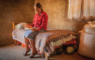 Tepehuan woman sitting on her bed and reading the Bible