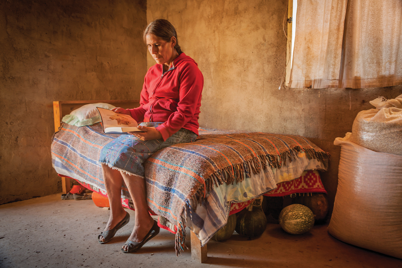 Tepehuan woman sitting on her bed and reading the Bible