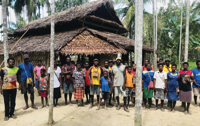 Kominimun people gathered beside a house