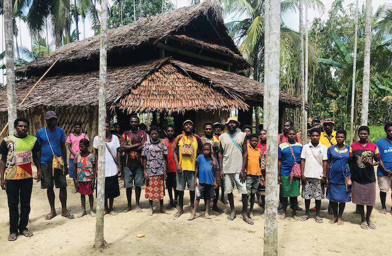 Kominimun people gathered beside a house