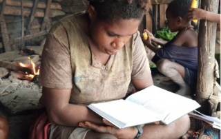 Moi woman reading Bible in a hut